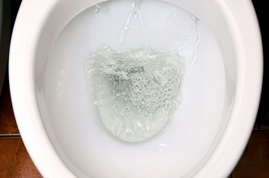 A photo of a white ceramic toilet bowl in the process of washing it off